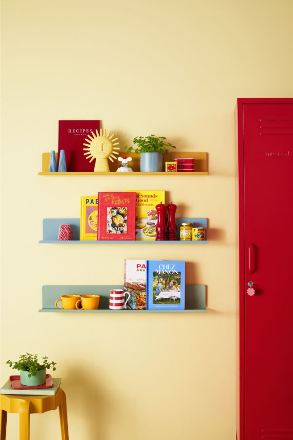 two shelves with books on them are next to a red locker and yellow table in the corner