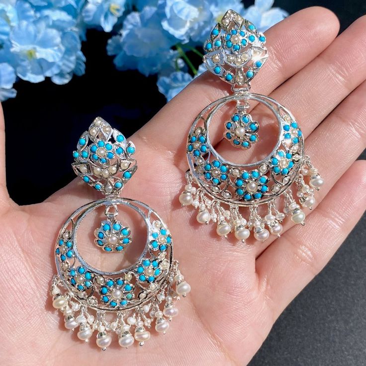 Featured is a traditional jadau chandbali earrings made on sterling silver and hand-studded with pearls and turquoises. The earrings have not been gold plating and are being presented in silver finish itself. The earrings close with a bombay screw mechanism. This classic design is crafted with precision and features a sterling silver base adorned with pearls and turquoise stones, all securely fastened with a traditional bombay screw closure. 22k Gold Jewelry Necklaces, 22k Gold Jewelry, Chandbali Earrings, Pearl Necklace Set, Gold Jewelry Necklace, Emerald Necklace, Turquoise Stones, Gold Bangle Bracelet, Pendant Set