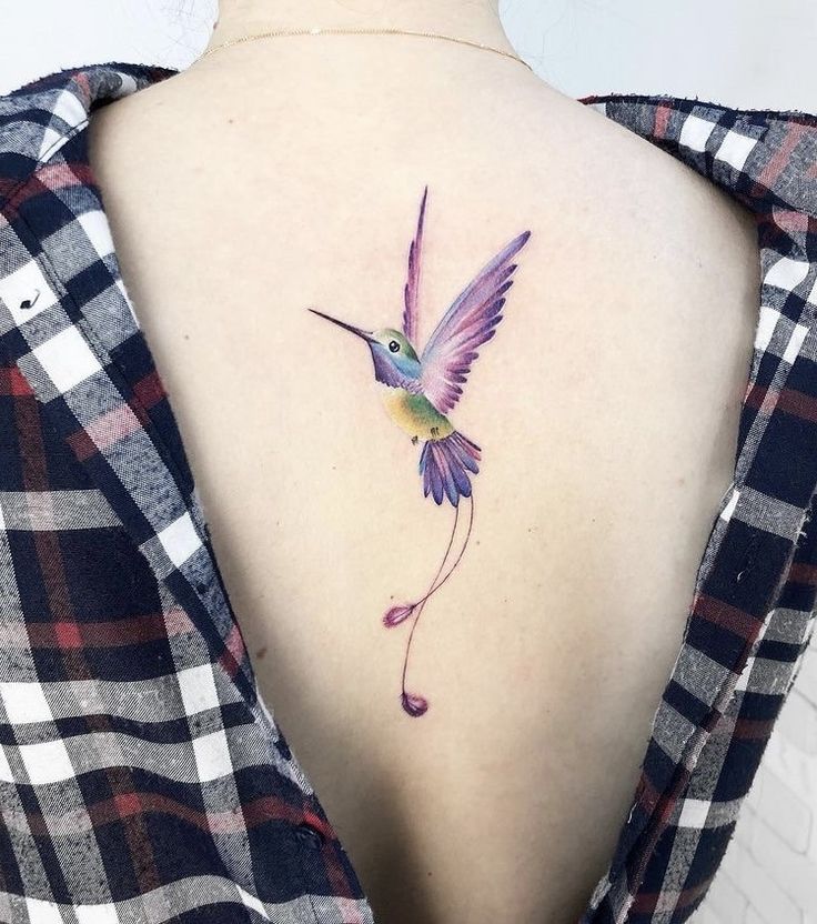 a hummingbird tattoo on the back of a woman's upper arm and neck