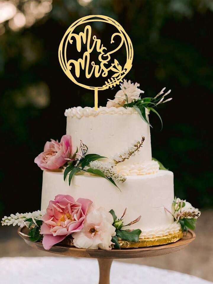 a wedding cake with pink flowers and greenery on top