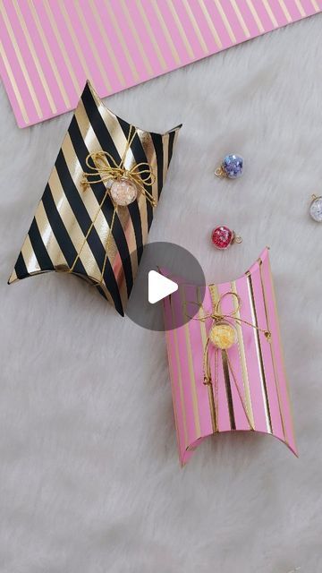 an open pink and black gift bag sitting on top of a white fur covered floor