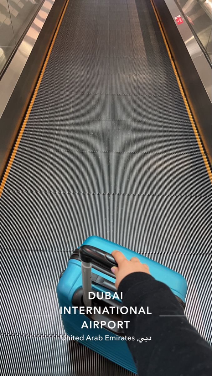 a person is pulling their luggage up an escalator at the airport with text that reads dubai international airport united arab emirates