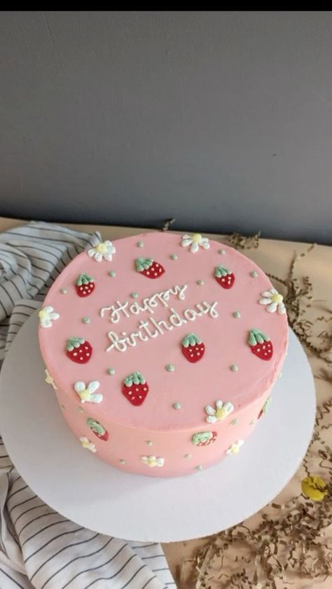 a pink birthday cake sitting on top of a white plate next to a striped napkin