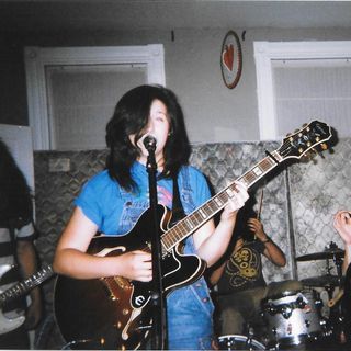 two people singing and playing guitars in a room