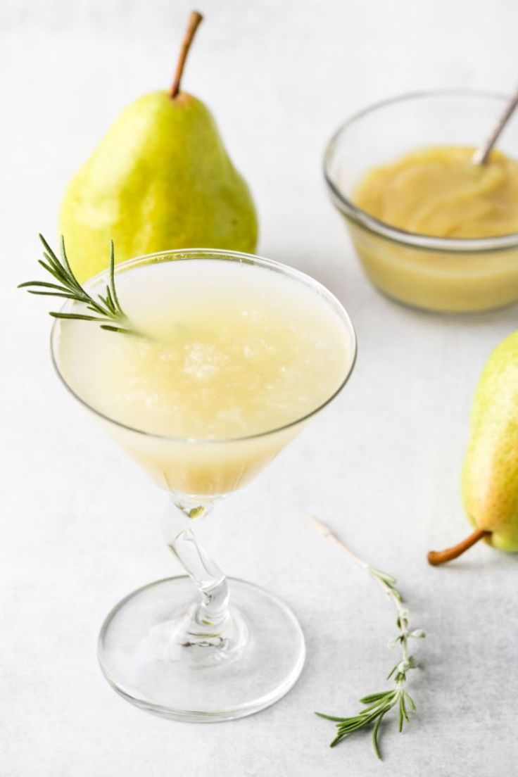 two glasses filled with pear martinis and garnished with rosemary