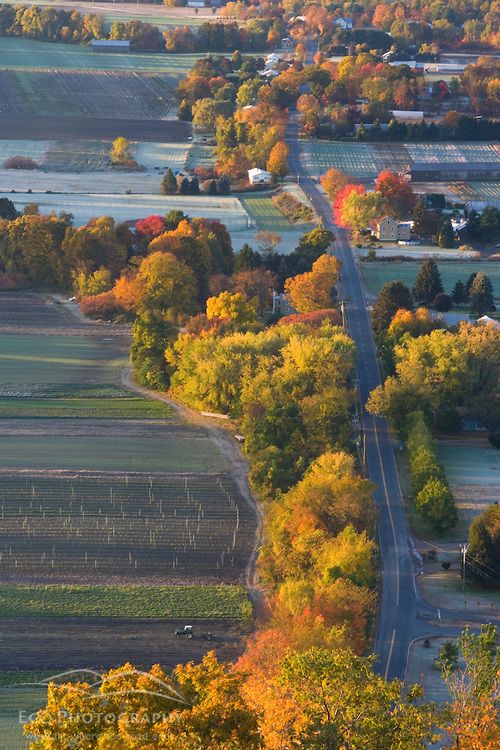 an aerial view of a country road surrounded by fields and trees in the fall colors