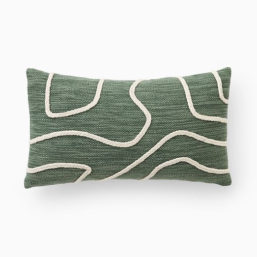 a green and white pillow with wavy lines on the front, sitting against a white background