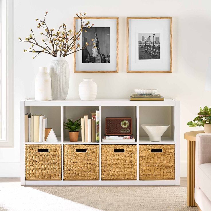 a white shelf with baskets and pictures on it next to a couch in a living room