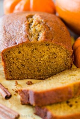 a loaf of pumpkin bread on top of a cutting board next to some oranges