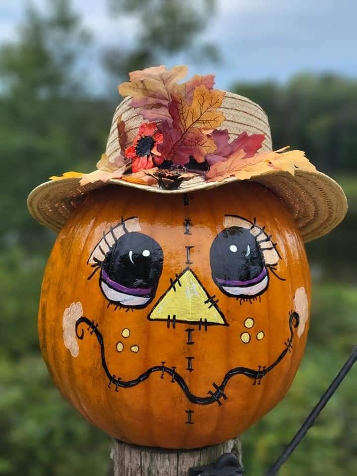 a pumpkin with a face painted on it's head, sitting on top of a wooden post