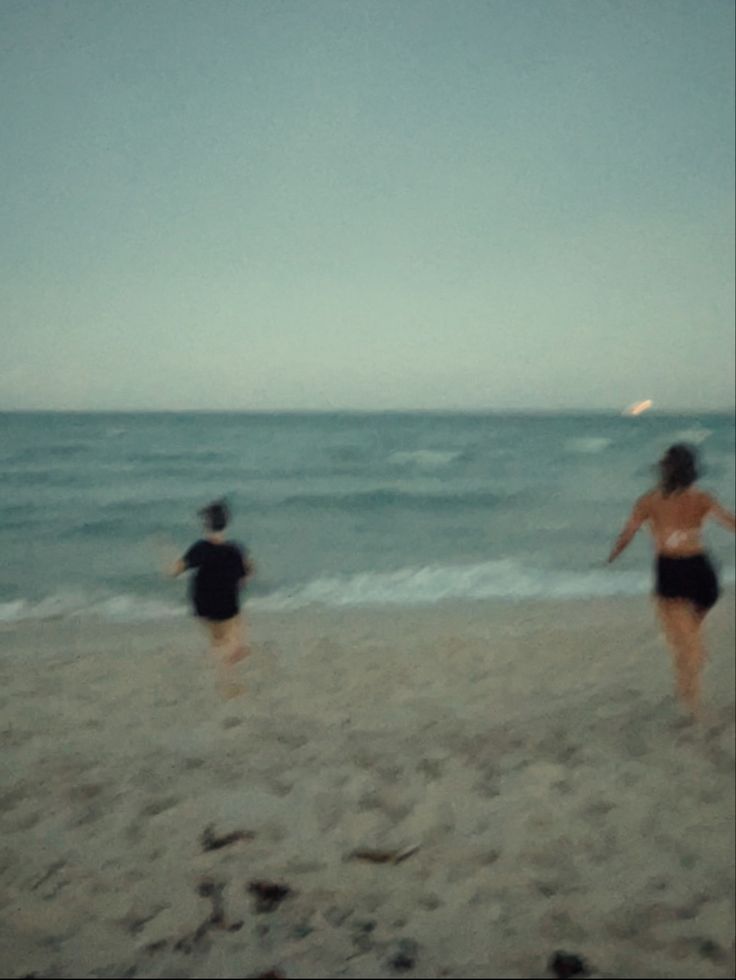 two people on the beach playing frisbee