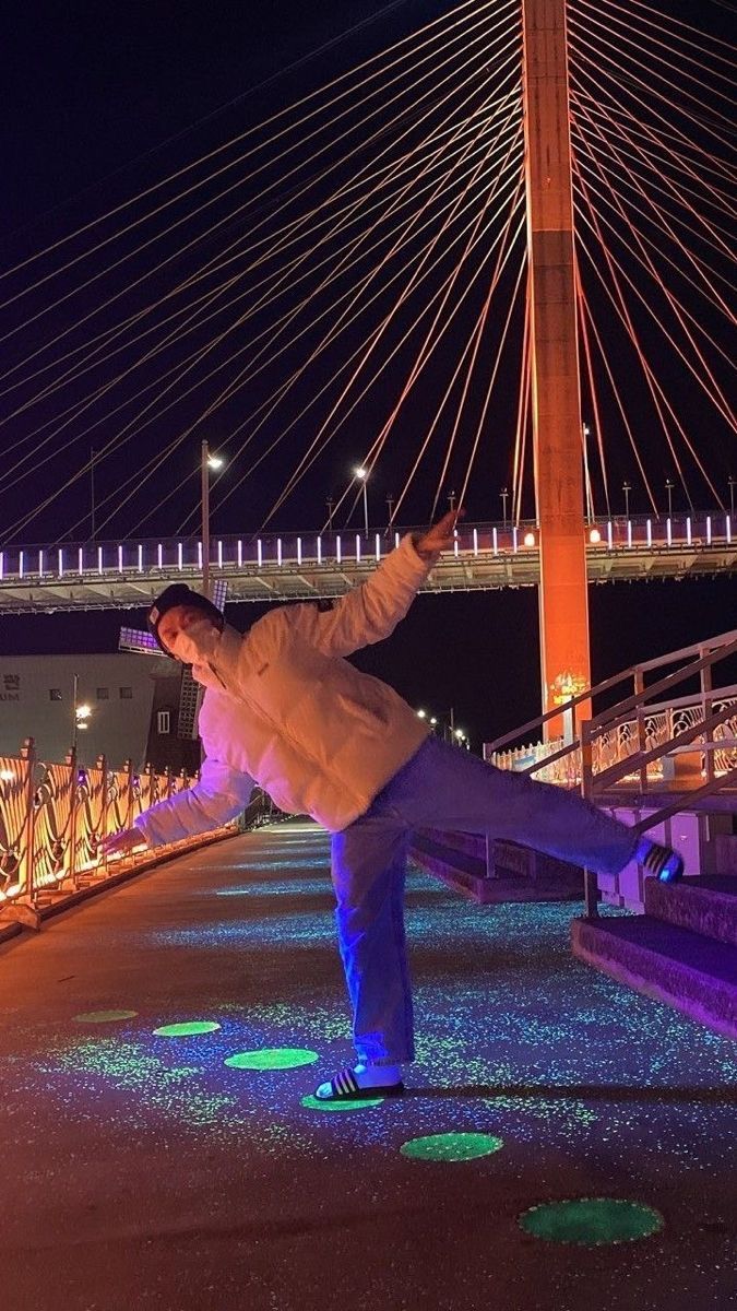 a man doing a trick on his skateboard in front of a bridge at night