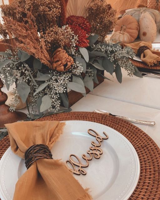 a table set for thanksgiving dinner with place settings and napkins on the plate, along with fall decorations