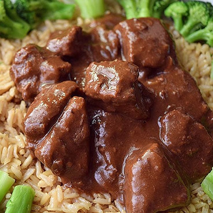 a plate with rice, broccoli and beef in gravy on it