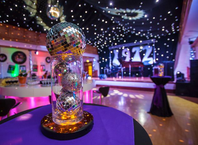 a disco ball on top of a table in a room with purple and black tables