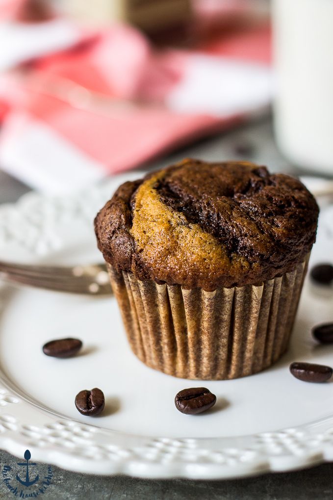 a chocolate muffin on a plate with coffee beans