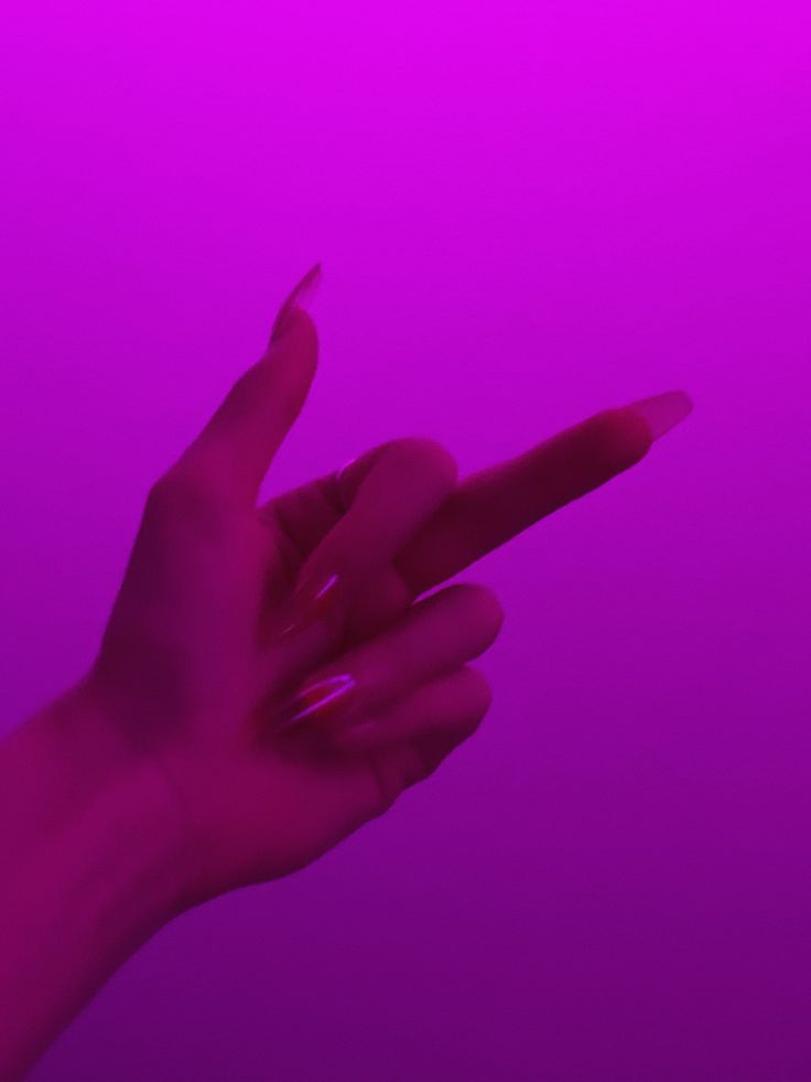 a person's hand holding up a cell phone in front of a purple background