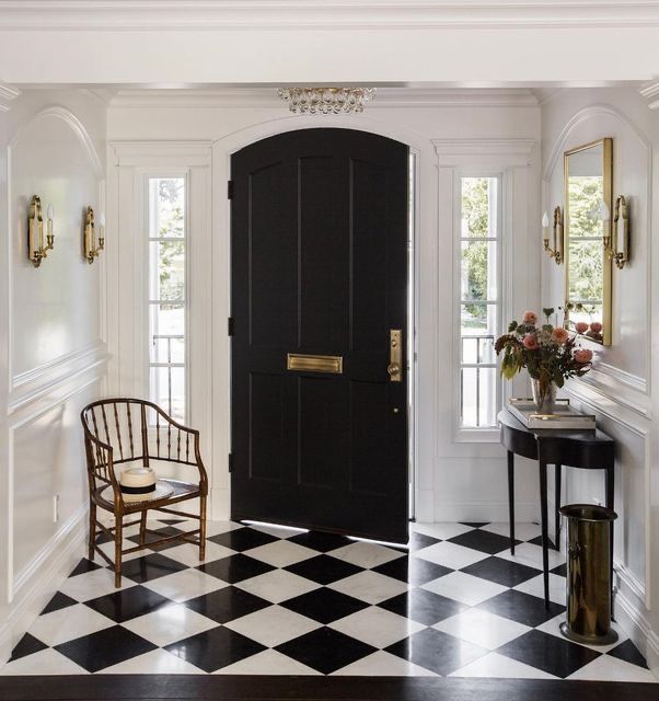 a black and white checkered floor with a chair in front of the door that leads to another room