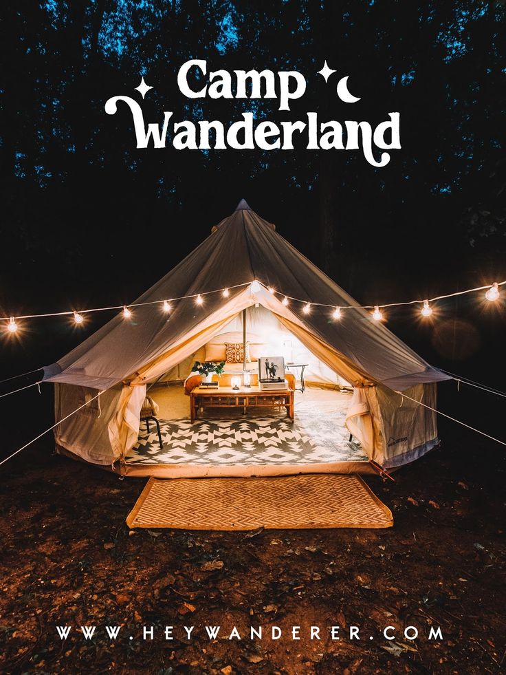 a tent is set up in the woods with string lights strung around it and a rug on the ground