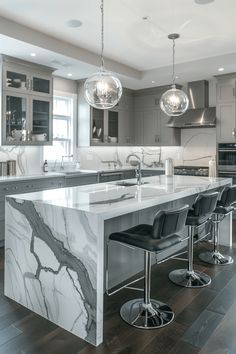 a large kitchen with marble counter tops and bar stools next to an island in the middle