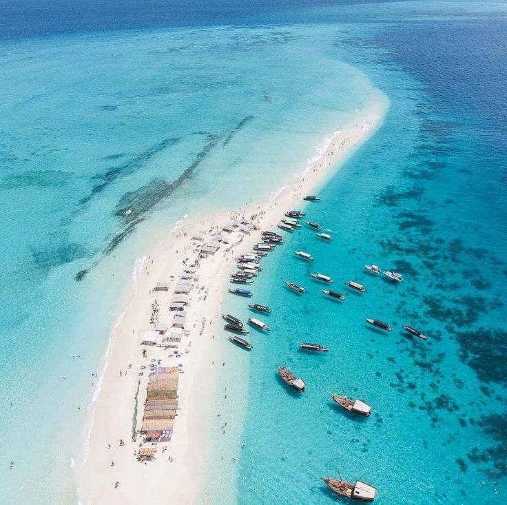 an aerial view of a beach with boats in the water