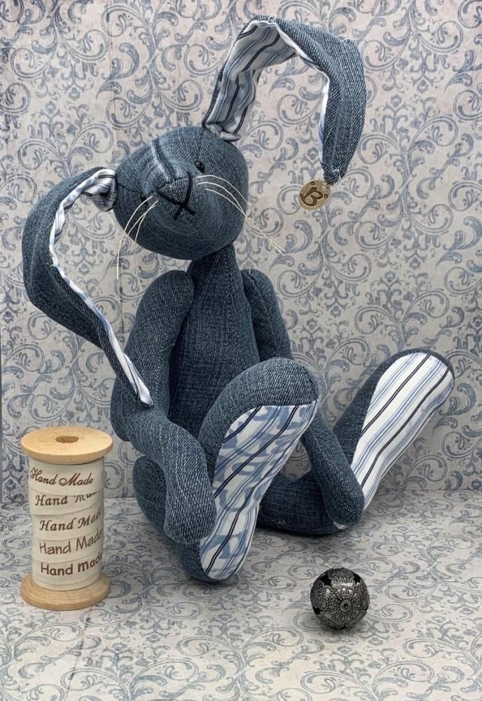 a stuffed rabbit sitting next to a roll of thread