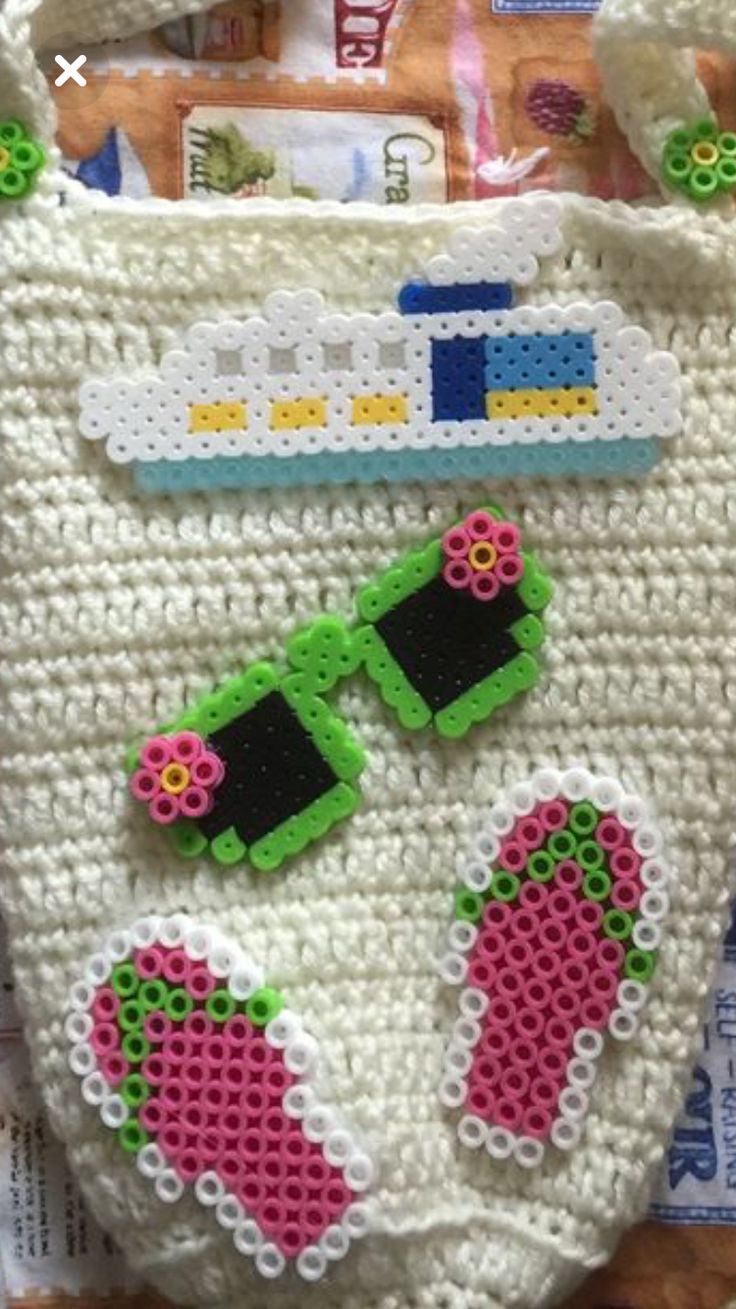 a crocheted bag with two pairs of sandals and sunglasses on the front is shown