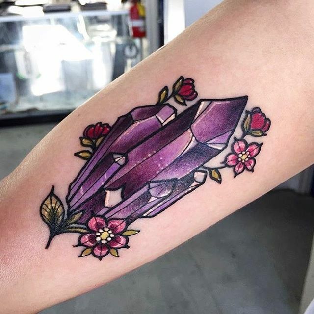 a woman's arm with a tattoo on it and an image of a purple diamond