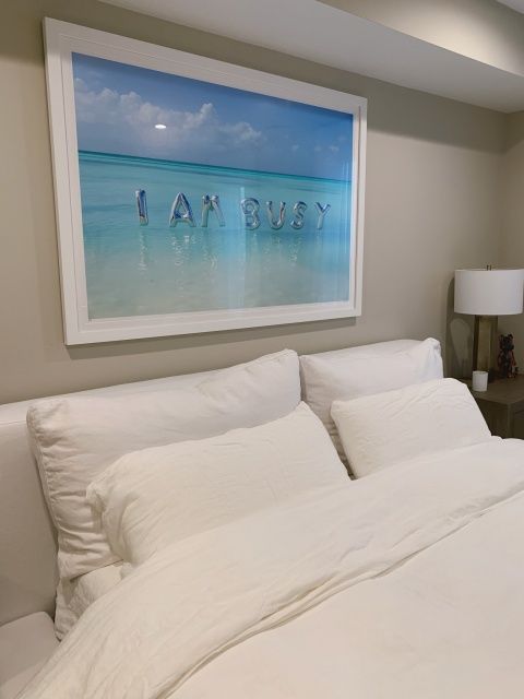 a large white bed sitting in a bedroom next to a painting on the wall above it