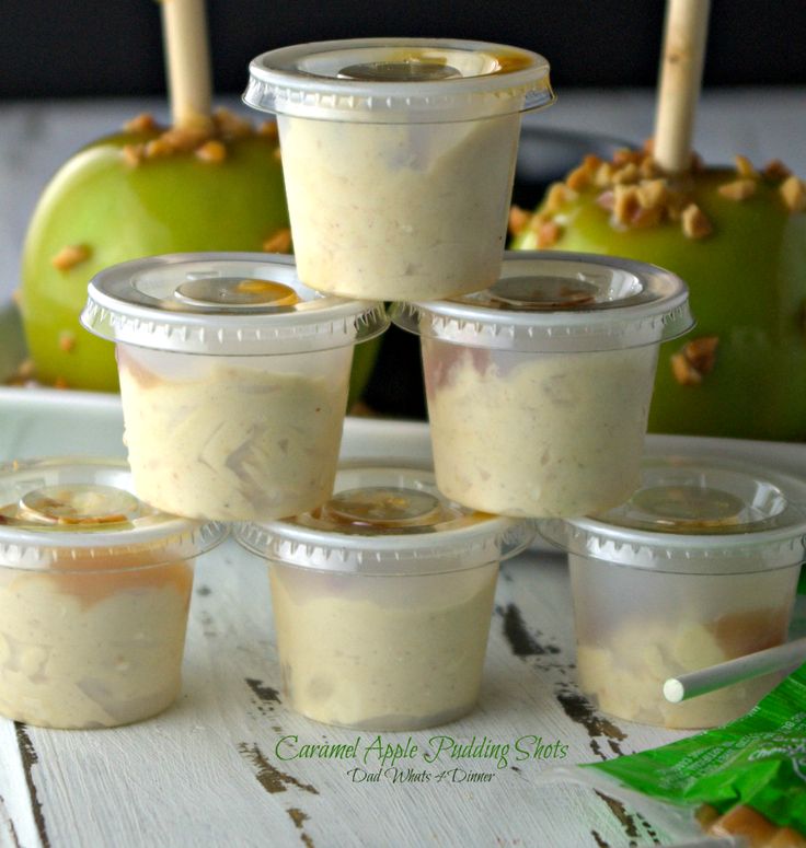 there are several cups with food in them on the table next to some green apples