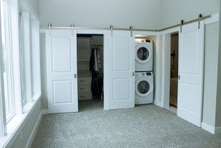 an empty laundry room with washer and dryer in the closet, next to two windows