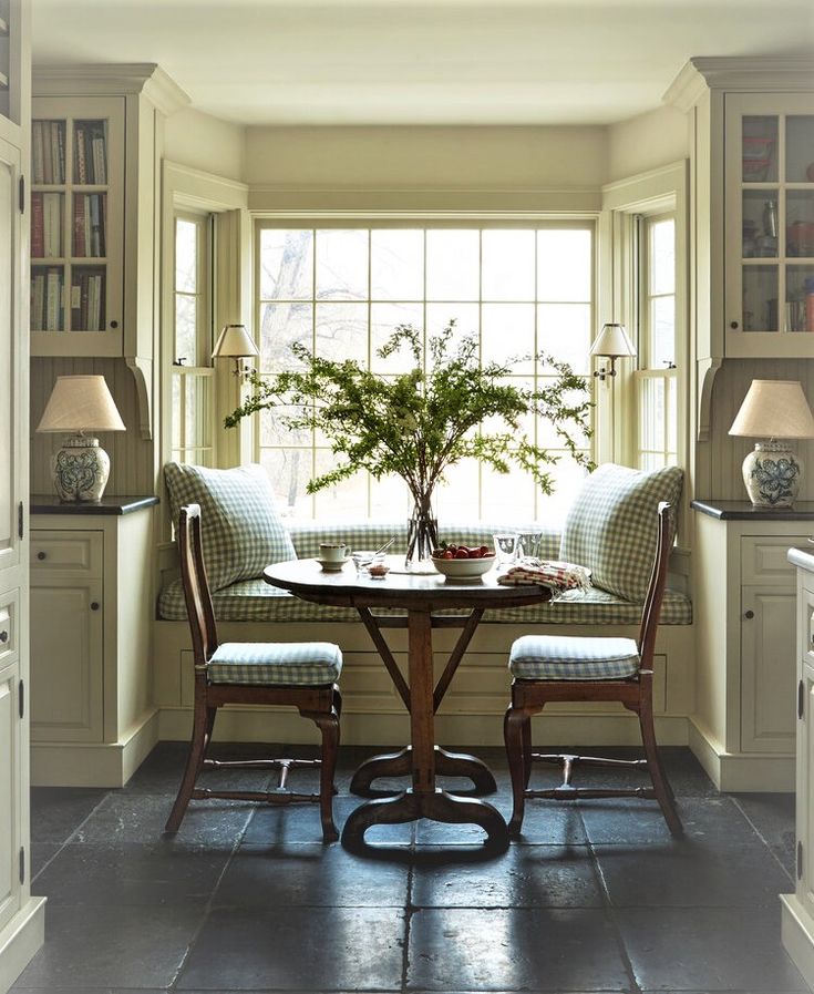 a table with two chairs and a potted plant in the window sill next to it