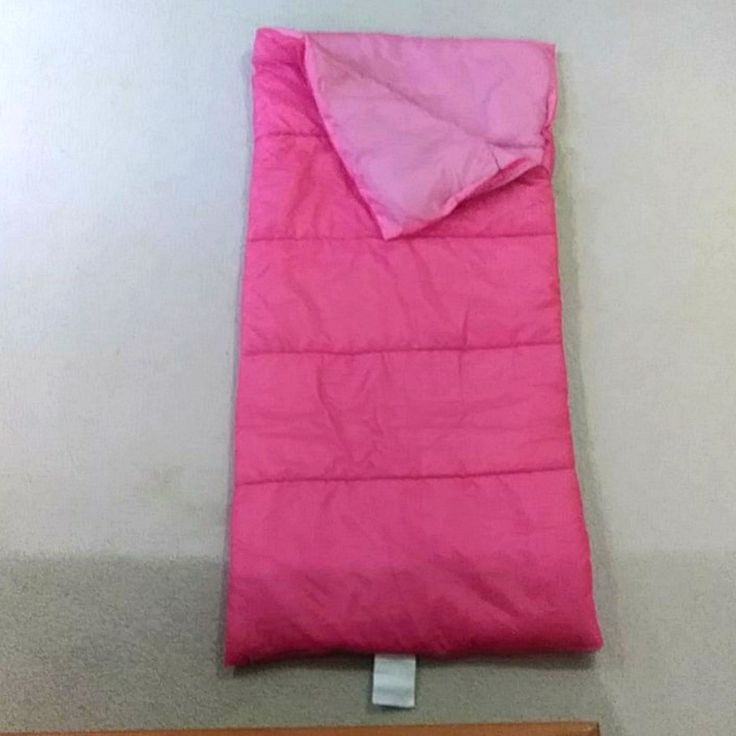 a pink sleeping bag sitting on the floor next to a wooden bed headboard and foot board