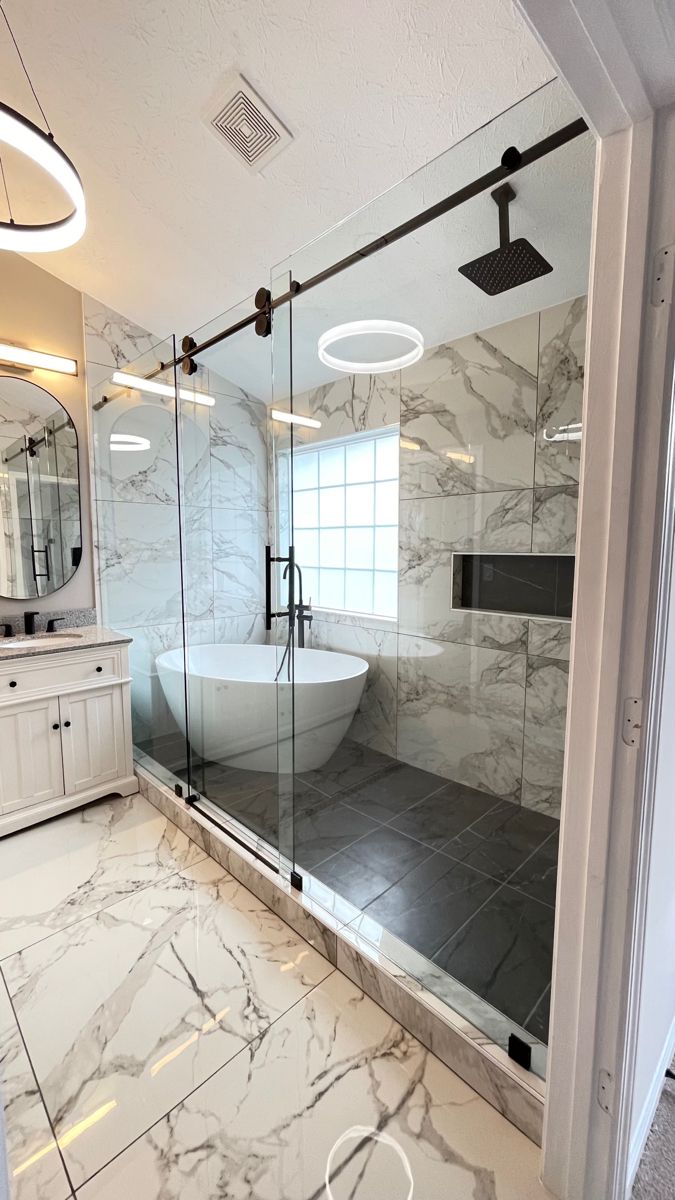 a bathroom with marble flooring and white walls, along with a glass enclosed shower stall