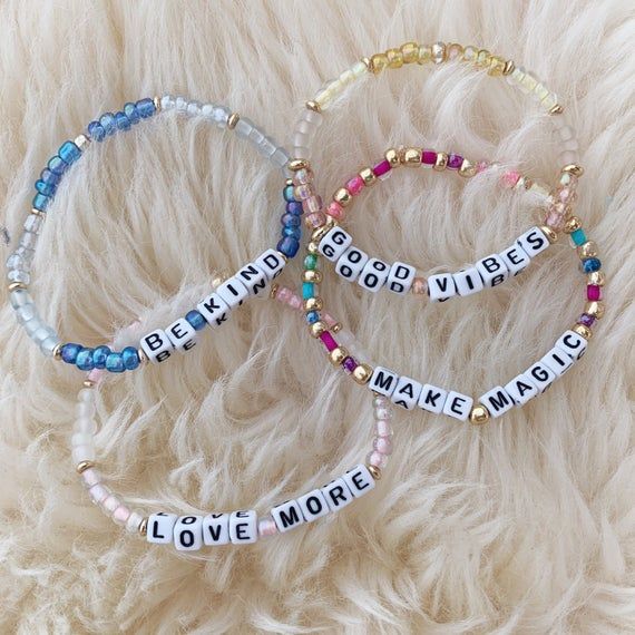 three bracelets with words on them sitting on a furry surface