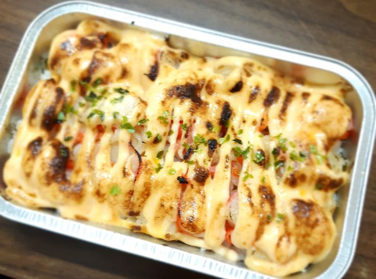 a casserole dish with meat and cheese on it sitting on a wooden table