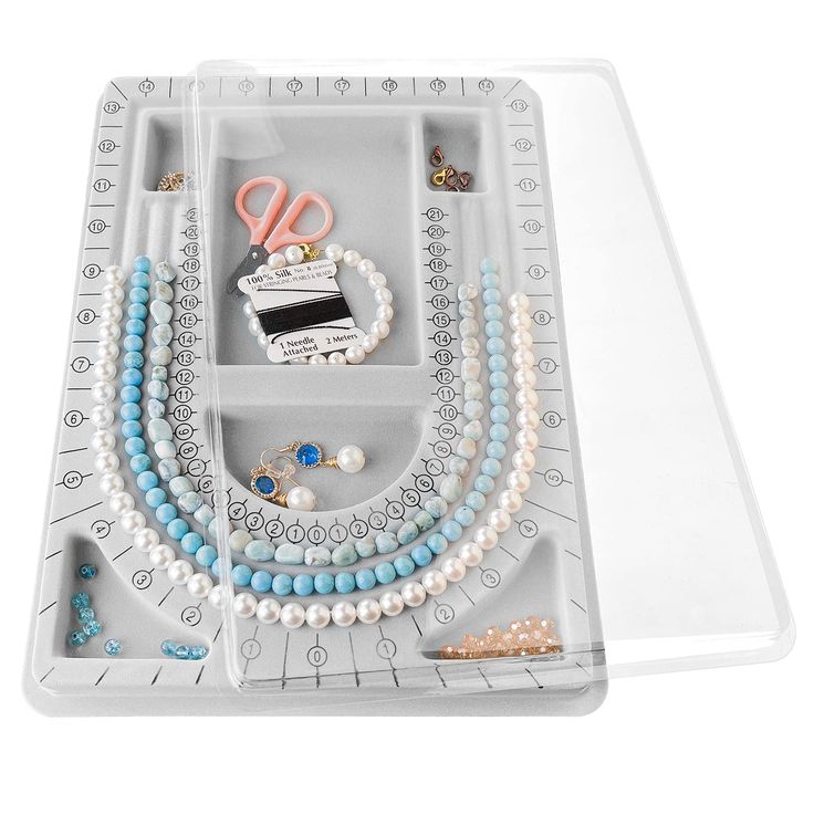 an assortment of jewelry is displayed in a plastic tray on a white surface with scissors and beads