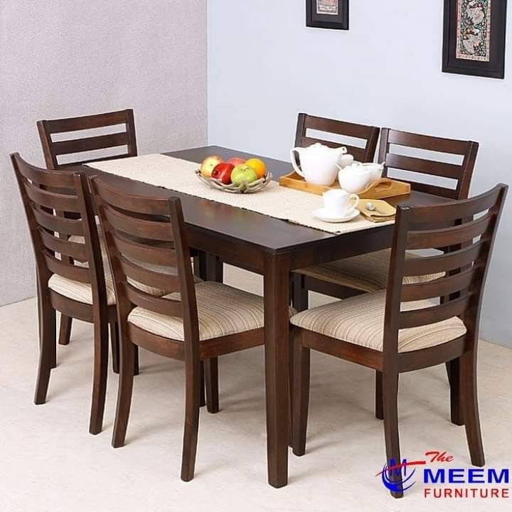 a wooden table with chairs around it and plates on top of the dining room table