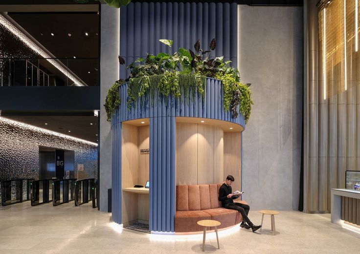 a man sitting on a bench in front of a plant filled room with blue walls