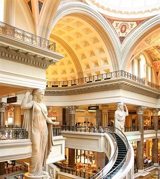 the interior of a shopping mall with statues and escalators on each floor,