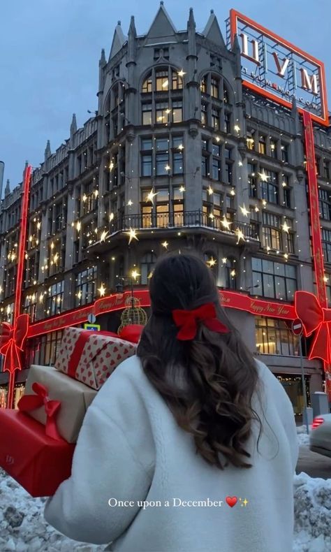 a woman is standing in front of a building with christmas lights and presents on it