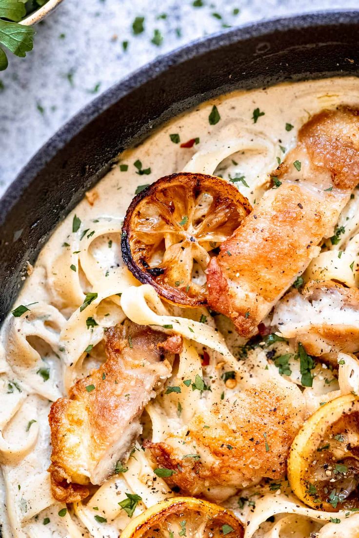 a pan filled with pasta and chicken covered in sauce, garnished with parsley