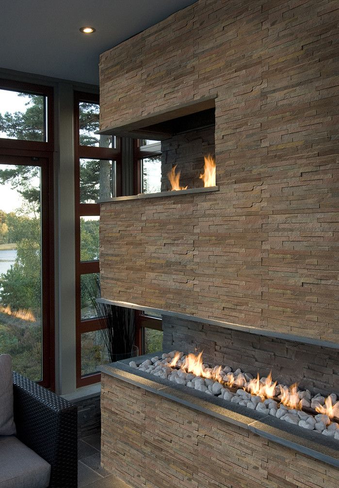 a fire place in the middle of a living room next to a couch and window