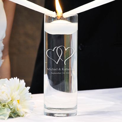 a close up of a candle on a table with flowers and a couple in the background