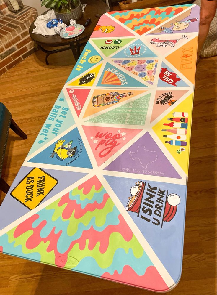 a long table covered in colorful stickers on top of a hard wood floor next to a blue chair