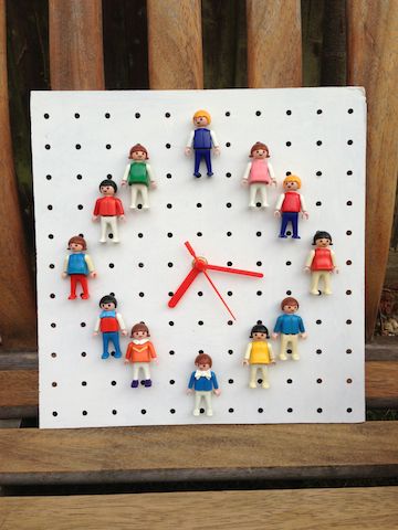 a clock made to look like people on a peg board