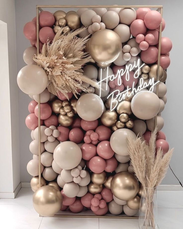 a happy birthday sign surrounded by balloons and feathers