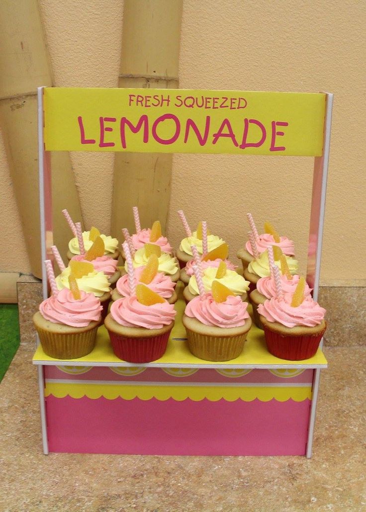 cupcakes with pink frosting and yellow icing are displayed on a stand