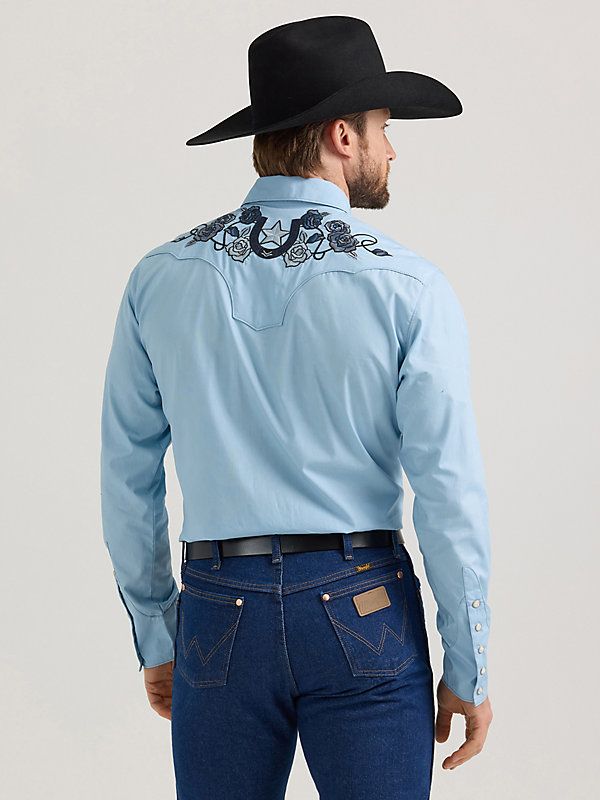 MADE FOR THE TAILORED COWBOY Class up any outfit you're wearing with the Wrangler® Rodeo Ben Western Snap Shirt. Inspired by our early years, this eye-catching take on the cowboy classic is meticulously made down to the smallest detail. It comes with a vintage-inspired pattern, fancy yokes, detailed embroidery, and pearl snaps for a polished look. Dressier than most, this embellished snap shirt for men is crafted from 100% cotton for long-lasting comfort and quality. Fitted Western Style Cotton Shirt, Relaxed Fit Cotton Shirt For Rodeo, Western Style Blue Relaxed Fit Tops, Western Blue Relaxed Fit Tops, Western Style Cotton Shirt For Spring, Fitted Cotton Western Top, Western Style Shirt For Ranch In Spring, Western Shirt For Spring Ranch Occasions, Western Style Shirt For Spring Ranch