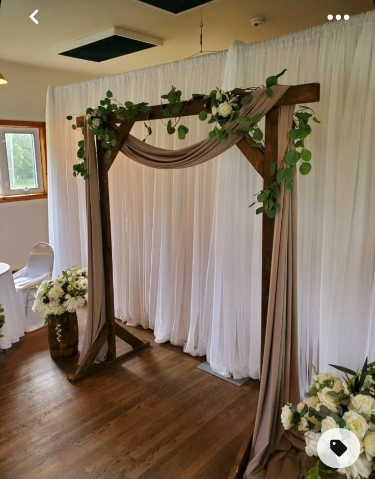 a wedding ceremony with white flowers and greenery on the side of the arch,